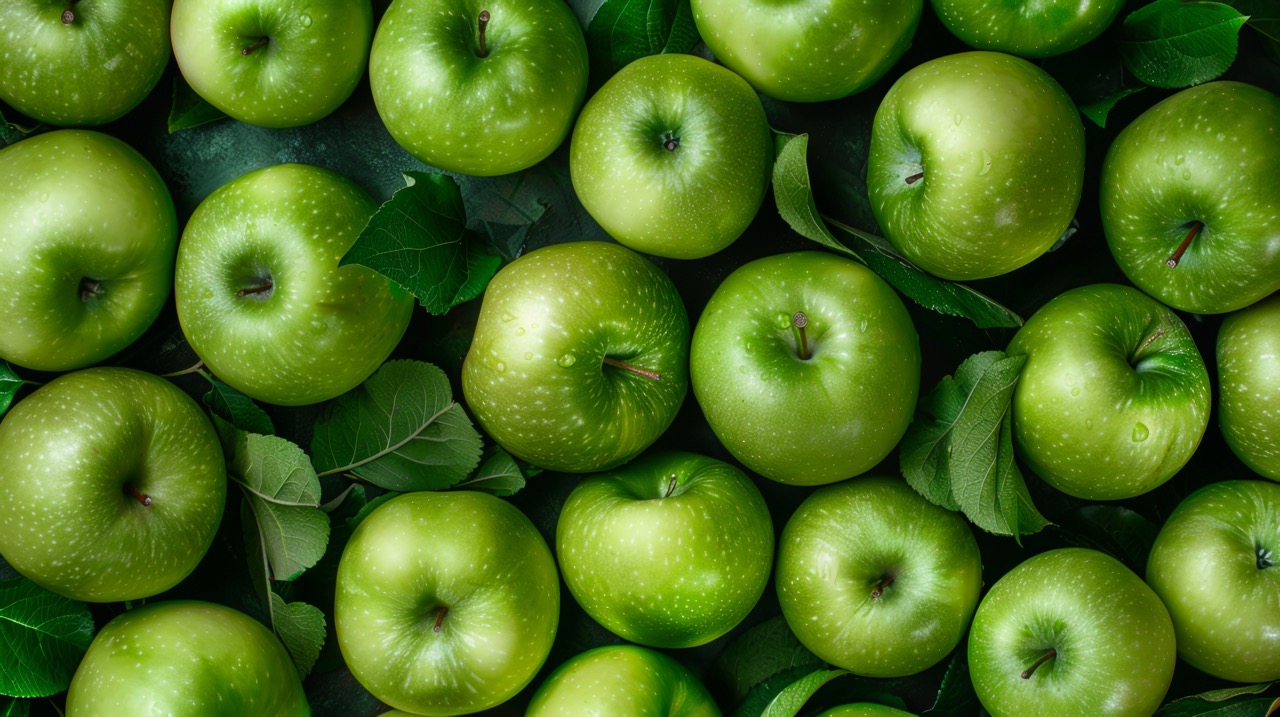 A bunch of green apples are on a table.